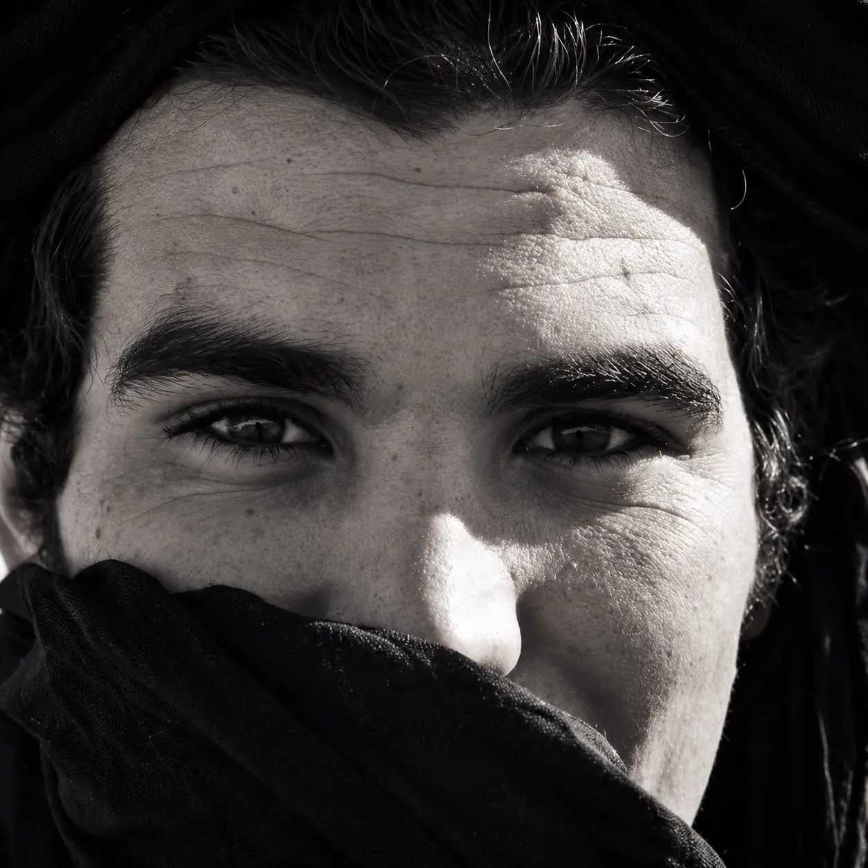 Retrato en blanco y negro de un hombre con turbante negro que le cubre la boca