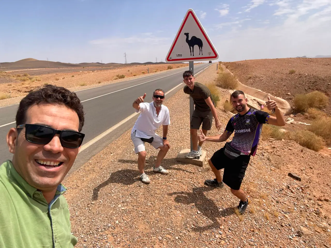Viaggiatori accanto a un cartello di attraversamento dromedari su una strada del sud del Marocco